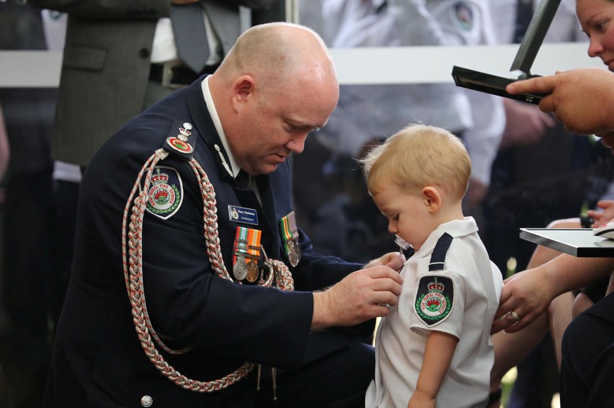 RFS Commissioner Shane Fitzsimmons presents a posthumous Commendation for Bravery and Service to the son of RFS volunteer Geoffrey Keaton at Keaton&#039;s funeral in Buxton, New South Wales, Australia ...