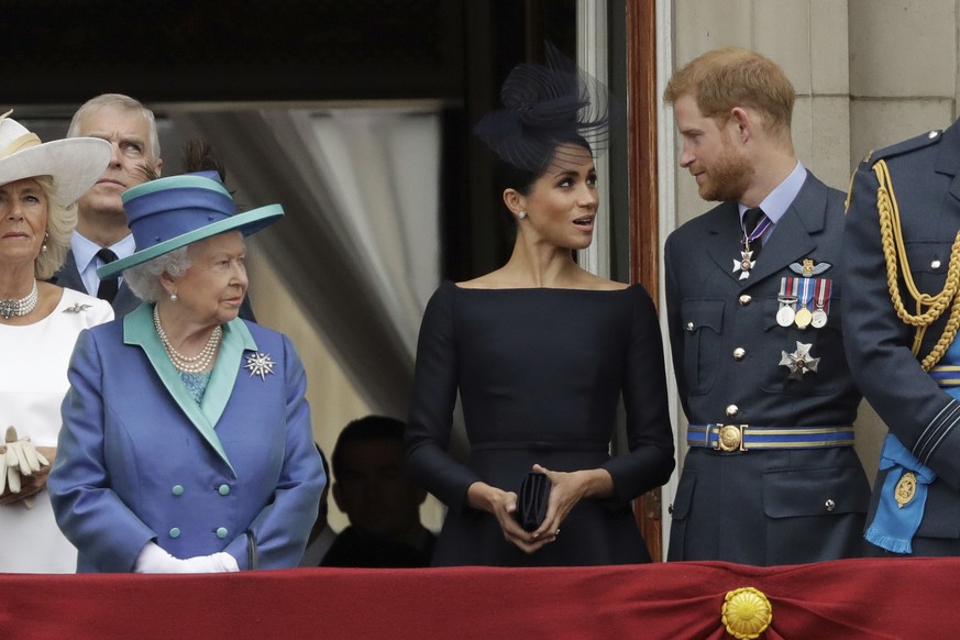 FILE - In this Tuesday, July 10, 2018 file photo Britain&#039;s Queen Elizabeth II, Meghan the Duchess of Sussex and Prince Harry stand on a balcony to watch a flypast of Royal Air Force aircraft pass ...