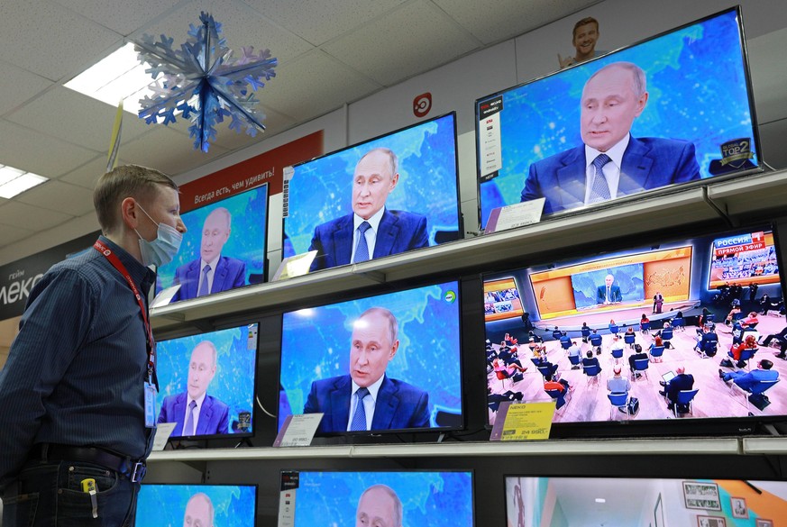 RYAZAN, RUSSIA - DECEMBER 17, 2020: A man watches a live TV broadcast of the 16th annual end-of-year news conference by Russia s President Vladimir Putin at a home appliances store. Alexander Ryumin/T ...