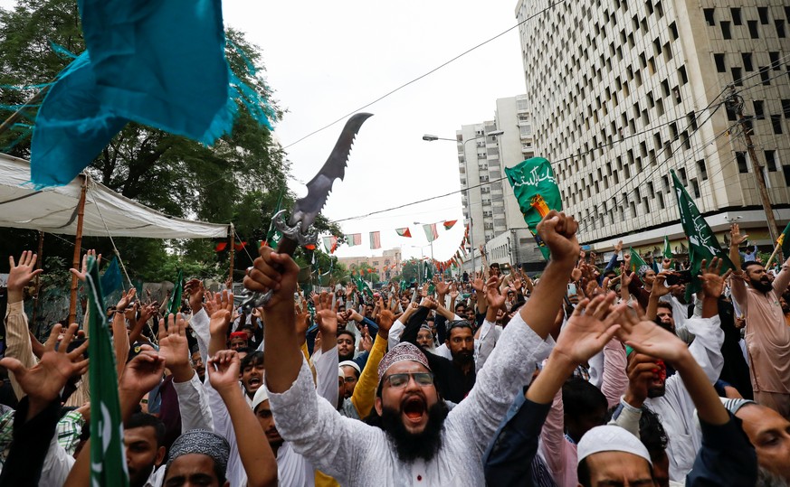 A supporter of religious and political party Tehreek-e-Labaik Pakistan (TLP) waves a dagger, as he chants slogans with others against the satirical French weekly newspaper Charlie Hebdo, which reprint ...