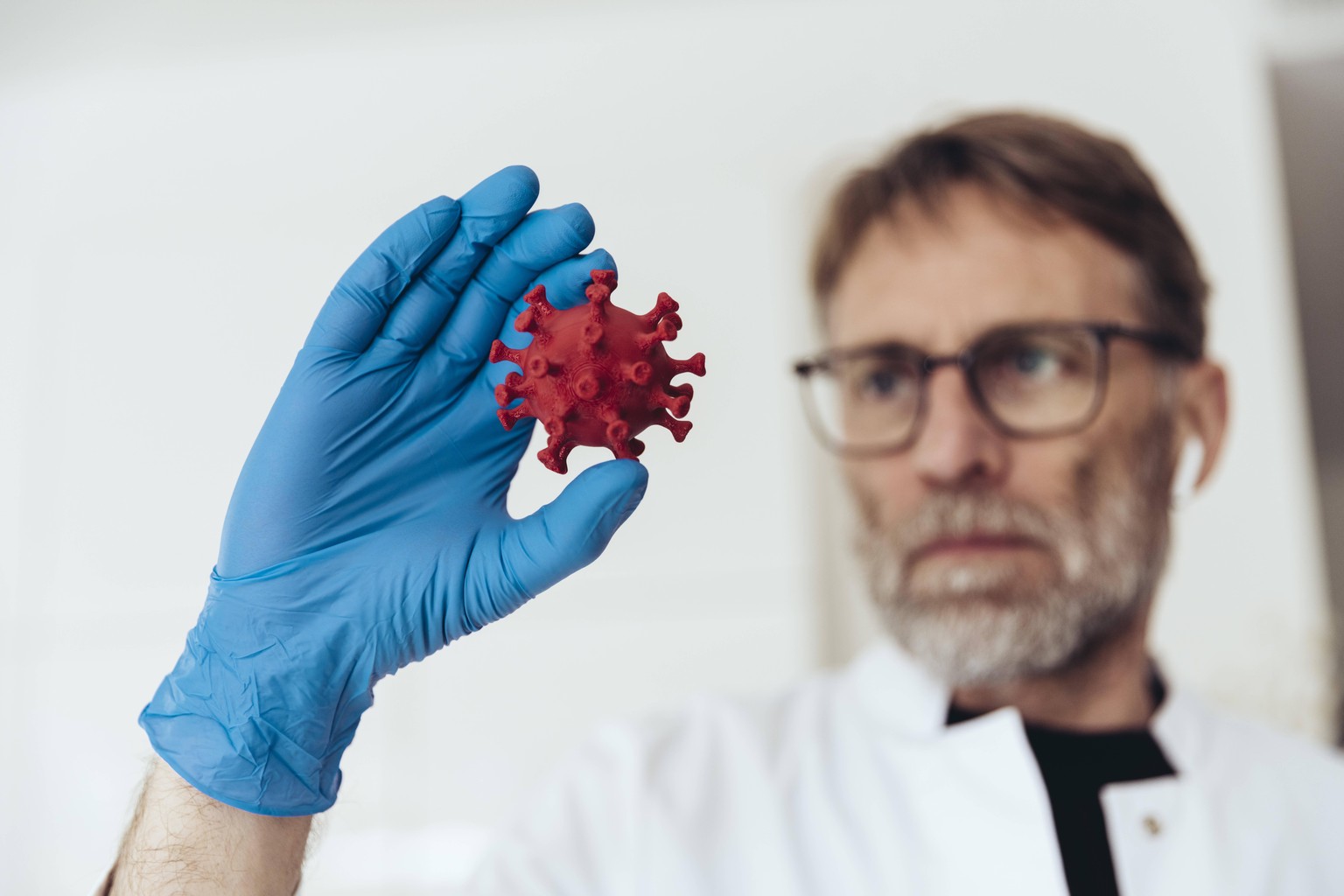 Scientist with medical glove, holding model of corona virus model released Symbolfoto MFF05368