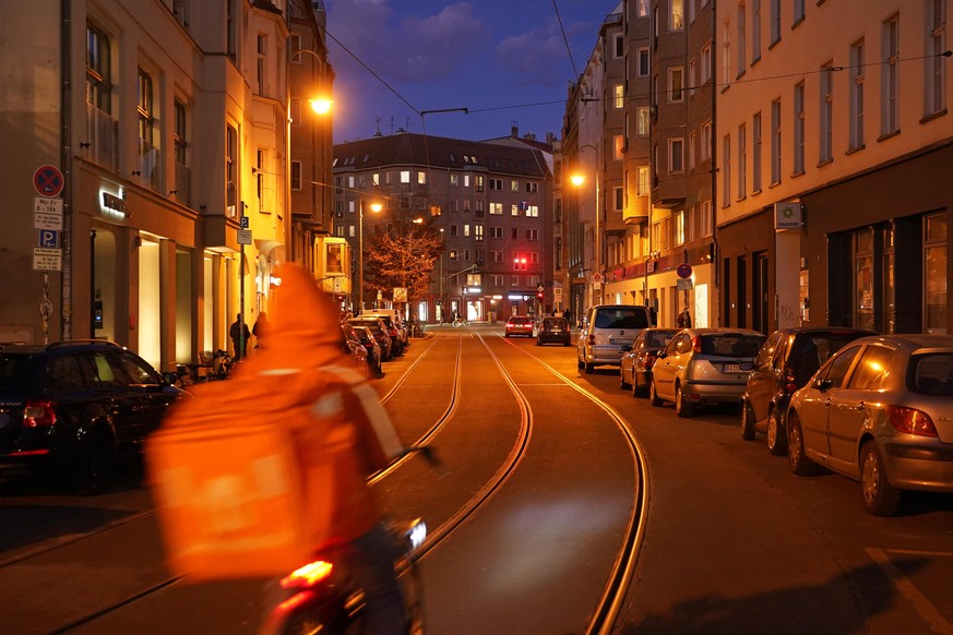 BERLIN, GERMANY - MARCH 05: A food courier from Lieferando rides down a street at twilight during the coronavirus pandemic on March 05, 2021 in Berlin, Germany. German authorities have confirmed the c ...