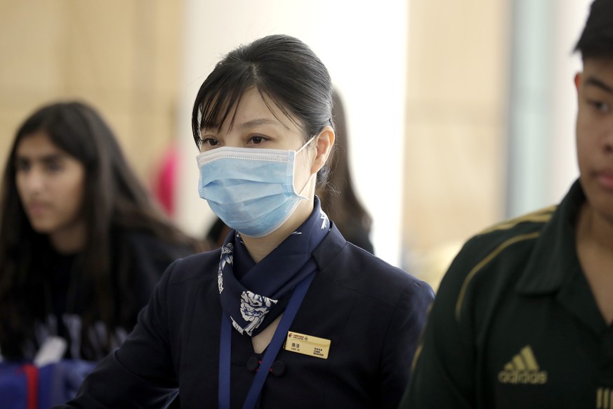A flight crew member from China Eastern Airlines leaves the airport wearing a face mask after arriving in Sydney Thursday, Jan. 23, 2020, on a flight from Wuhan, China. China closed off a city of more ...