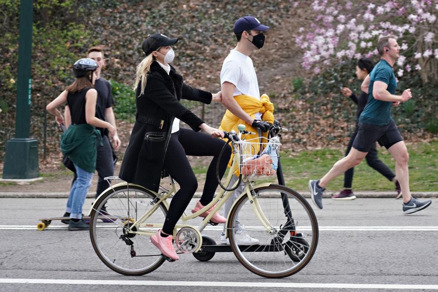 NEW YORK, NEW YORK - MARCH 20: A couple riding a bike and scooter wearing protective masks in Central Park as the coronavirus continues to spread across the United States on March 20, 2020 in New York ...
