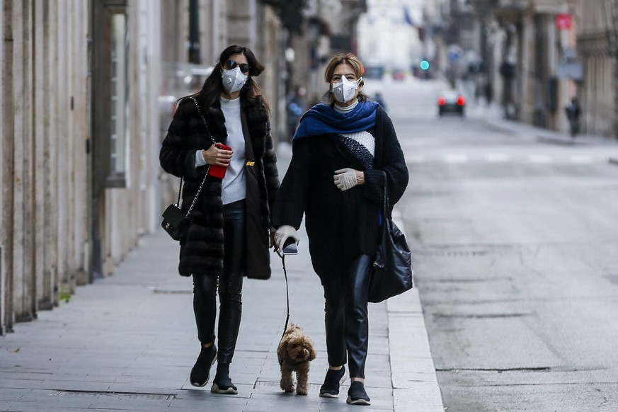 Coronavirus emergency in Rome Two Women with antivirus masks and gloves take their dog for a walk on Via Del Corso in Rome *** Coronavirus emergency in Rome Two women with antivirus masks and gloves t ...