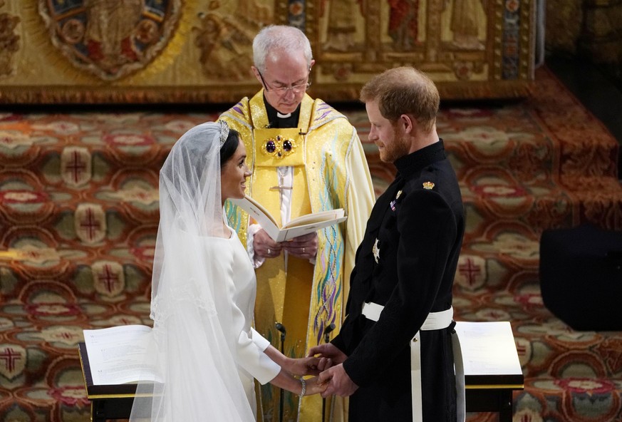TOPSHOT - Britain&#039;s Prince Harry, Duke of Sussex (R) and US actress Meghan Markle (L) stand facing each other hand-in-hand before Archbishop of Canterbury Justin Welby (C) during their wedding ce ...
