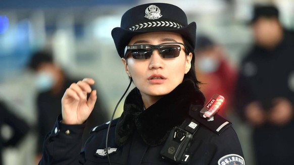 Polizistin mit Überwachungsbrille an einem Bahnhof in China.