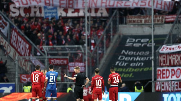 Referee Christian Dingert, center, talks to Hoffenheim and Munich players while Munich fans on the tribune display a banner reading &quot;Hopp stays a son of a bitch&quot; during a German Bundesliga s ...