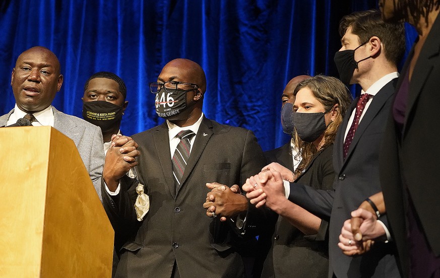 Floyd family attorney Ben Crump, left, asked all to clasp hands during a press conference to announce a $27 million civil lawsuit settlement between the Floyd family and the City of Minneapolis Friday ...