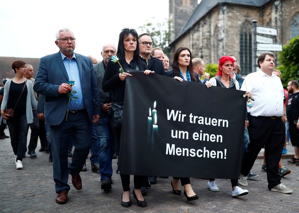People hold a banner reading: &quot;We mourn for a human&quot; as they march to the crime scene during a gathering organised by Germany&#039;s anti-immigration party Alternative for Germany (AfD), aft ...