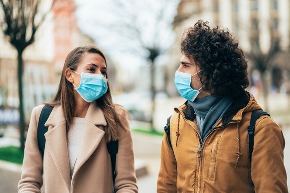 Young couple meet in quarantine outside on the city street wearing face protective mask to prevent Coronavirus and anti-smog