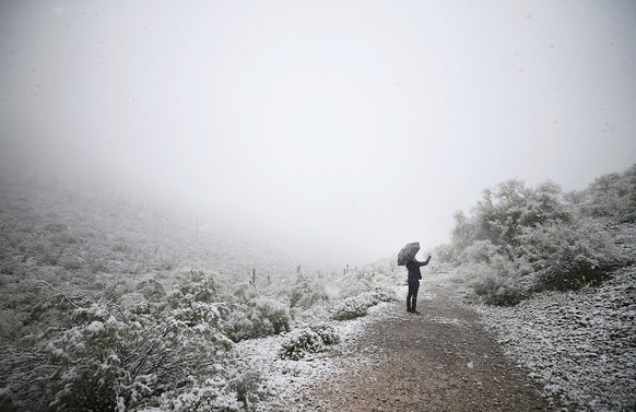 A man takes a photo of the desert landscape near Sentinel Peak covered in snow on Friday, Feb. 22, 2019, in Tucson, Ariz. Snow fell and accumulated in central and downtown Tucson on Friday, surprising ...