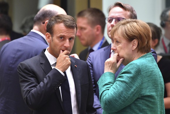 German Chancellor Angela Merkel, right, speaks with French President Emmanuel Macron during a round table meeting at an EU summit in Brussels, Thursday, June 28, 2018. European Union leaders meet for  ...