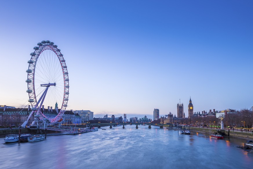 Skyline of London before sunrise with famous landmarks, Big Ben, Houses of Parliament, boat and clear blue sky - London, UK