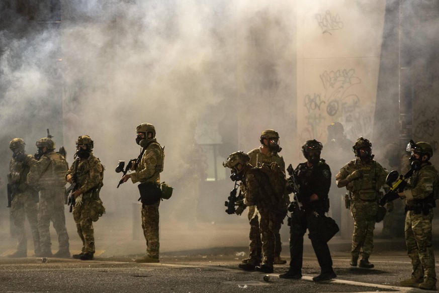 July 19, 2020, Portland, Oregon, USA: Federal police move through tear gas clouds in front of the Hatfield Federal Courthouse while dispersing a crowd of about a thousand people during the 53rd night  ...