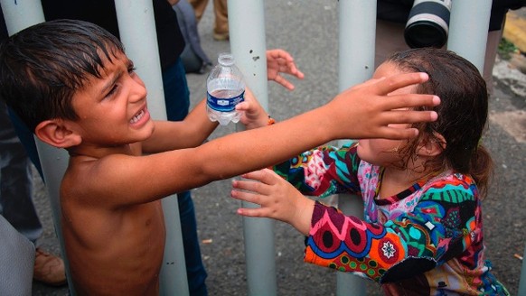 Zwei Kinder, die zu einer Gruppe 
honduranischer Migranten gehören, warten auf einer Brücke, die Guatemala
und Mexiko verbindet: Unter den Migranten sind viele Kinder und Frauen.