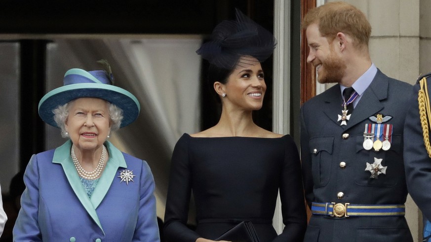 FILE - In this Tuesday, July 10, 2018 file photo Britain&#039;s Queen Elizabeth II, and Meghan the Duchess of Sussex and Prince Harry watch a flypast of Royal Air Force aircraft pass over Buckingham P ...