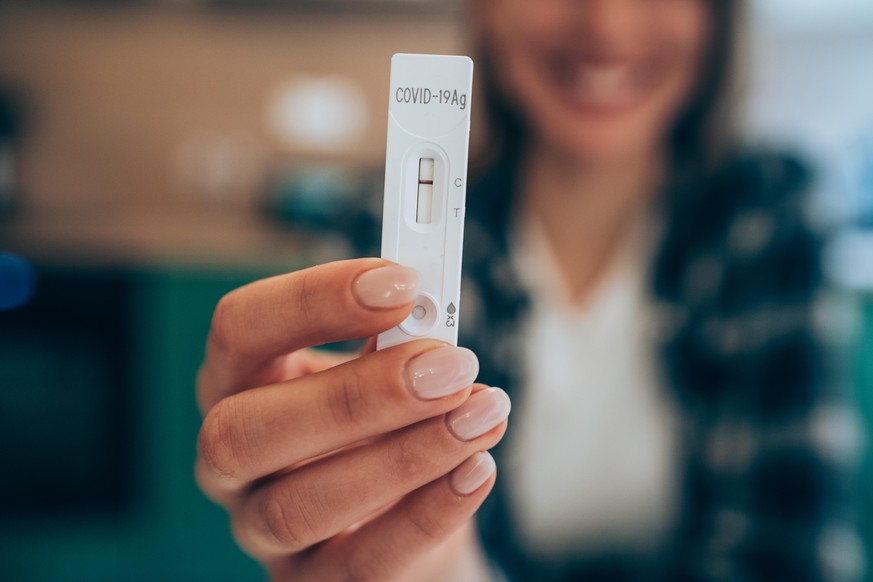 Close-up shot of woman&#039;s hand holding a negative test device. Happy young woman showing her negative Coronavirus/Covid-19 rapid test. Focus is on the test.