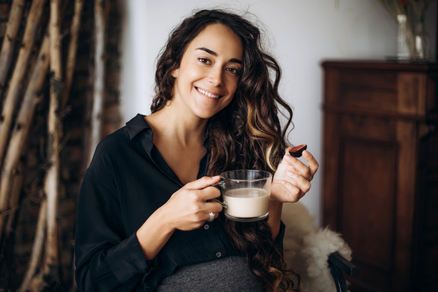 Portrait of a beautiful pregnant woman with a cup of coffee and figs in hands at home.