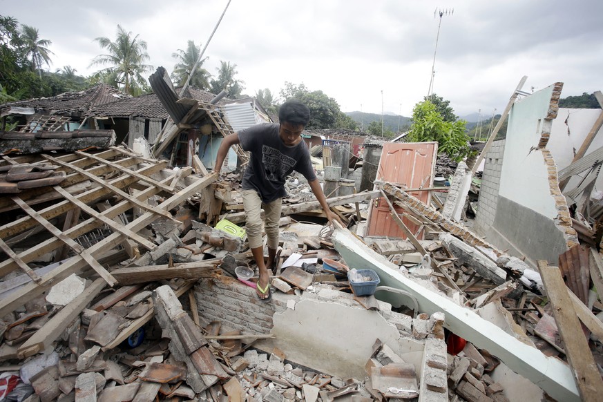 A man walks through debris from Sunday&#039;s earthquake in West Lombok, Indonesia, Saturday, Aug. 11, 2018. Scientist say the powerful Indonesia earthquake that killed more than 300 people lifted the ...