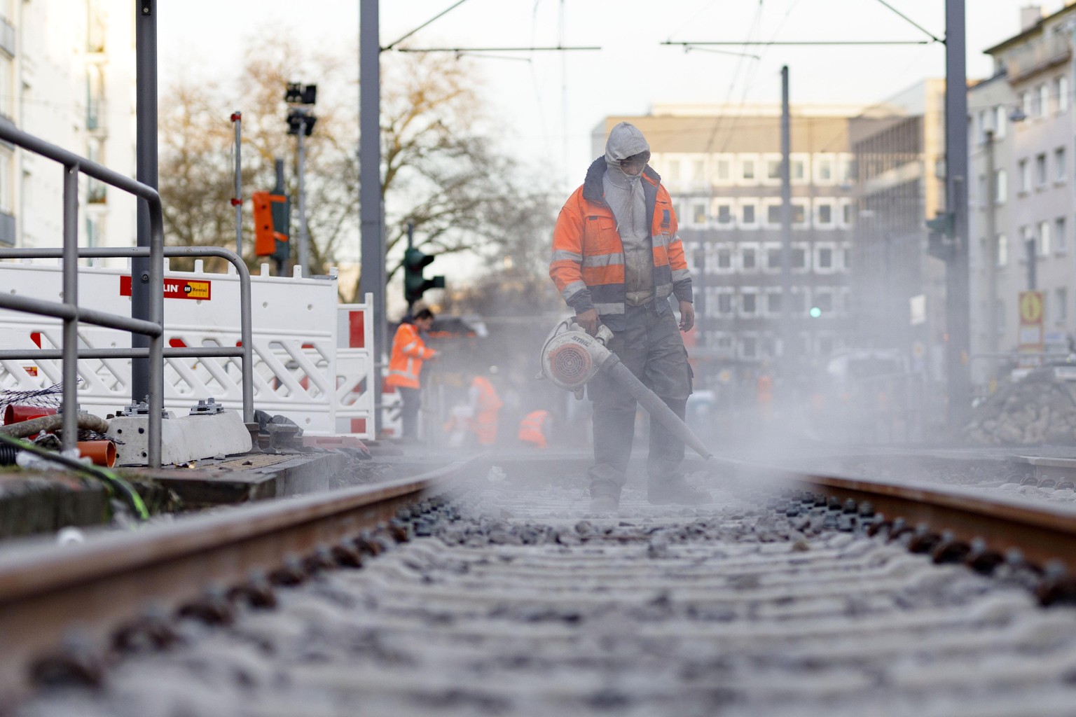 Ein Bauarbeiter bläst Betonstaub von Bahnschienen. Köln, 27.03.2020 | Verwendung weltweit