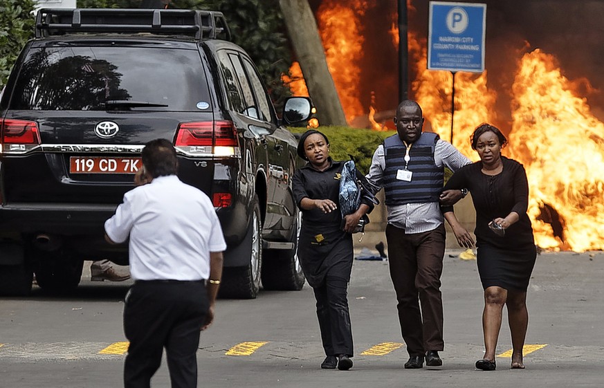 Security forces help civilians flee the scene as cars burn behind, at a hotel complex in Nairobi, Kenya Tuesday, Jan. 15, 2019. Terrorists attacked an upscale hotel complex in Kenya&#039;s capital Tue ...