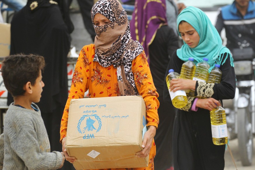 FILE PHOTO: Women carry food aid given by UN&#039;s World Food Programme in Raqqa, Syria April 26, 2018. REUTERS/Aboud Hamam/File Photo