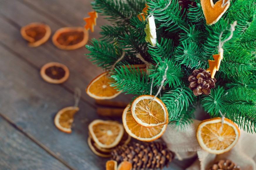 Closeup of dried citrus slices on the Christmas tree on wooden rustic background. Alternative eco friendly Christmas tree decoration concept. Selective focus.