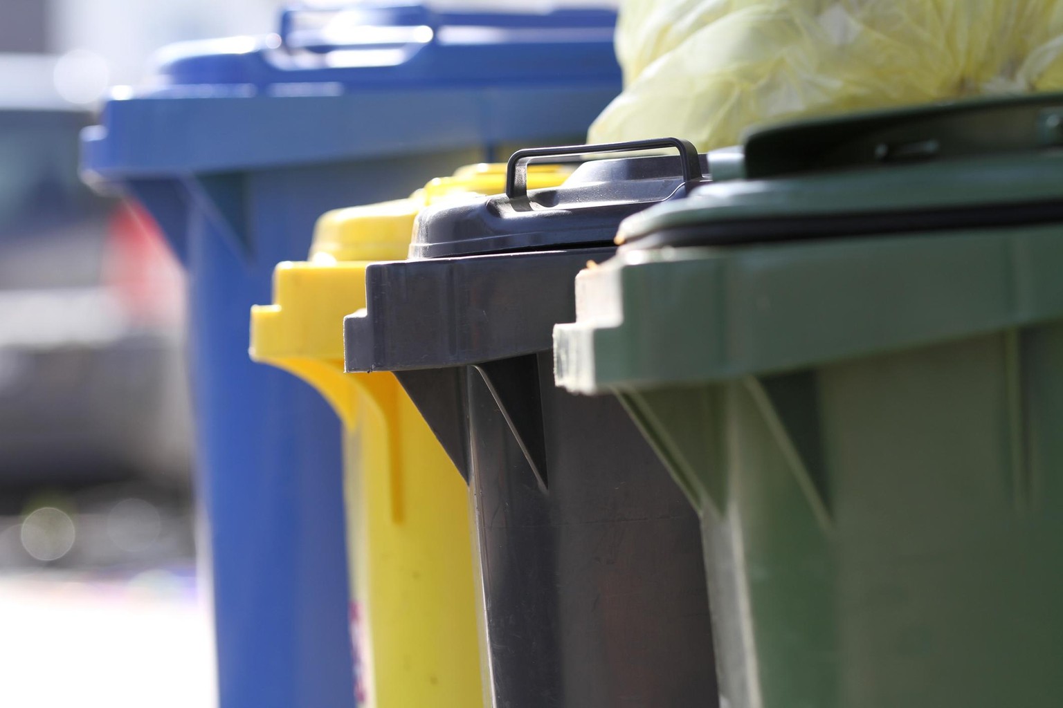 Garbage cans in different colors (blue, yellow, green, grey) in Germany.