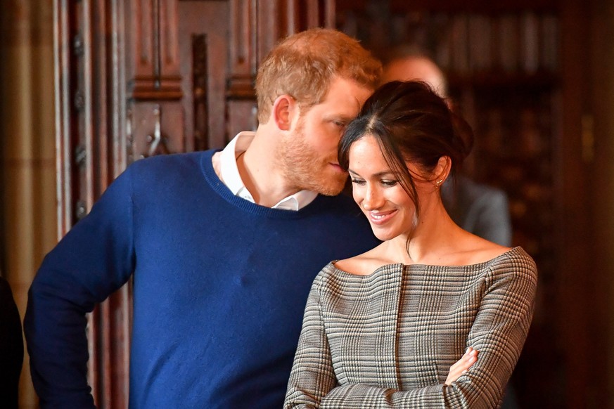 Prince Harry visit to Cardiff Castle. Prince Harry whispers to Meghan Markle as they watch a performance by a Welsh choir in the banqueting hall during a visit to Cardiff Castle. Picture date: Thursda ...