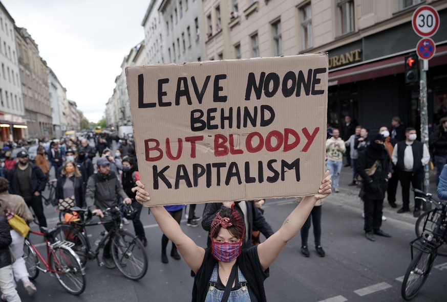 Eine Demonstrantin hält ein Plakat mit der Aufschrift &quot;Leave no one behind but bloody kapitalism&quot; auf der Oranienstraße in Kreuzberg hoch.