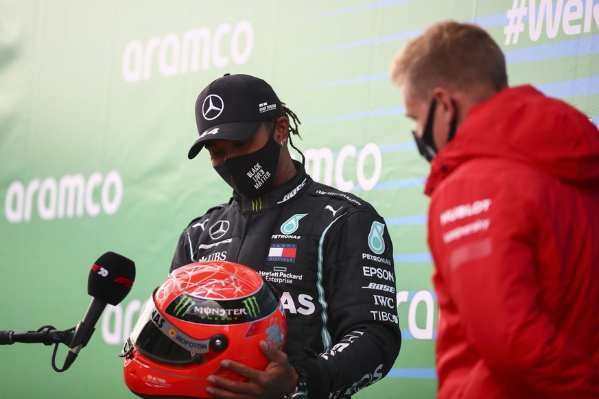 Mercedes driver Lewis Hamilton, left, of Britain receives a helmet of former German driver Michael Schumacher from Mick Schumacher, right, after he wins the Eifel Formula One Grand Prix at the Nuerbur ...