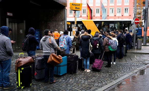 Commuters line up for a bus to the airport in front of a Deutsche Bahn building during a rail workers&#039; strike across the country due to a pay dispute with Deutsche Bahn, in Munich, Germany Decemb ...