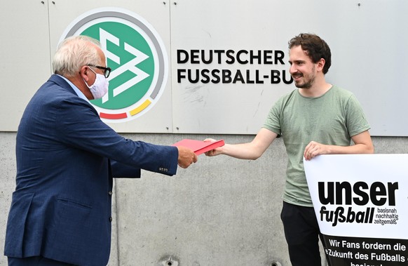 Manuel Gaber (r) von der Fan-Initiative «Unser Fußball» übergibt vor der DFB-Zentrale eine Erklärung zur geforderten Reform des Profigeschäfts an Fritz Keller, Präsident des Deutschen Fußball-Bundes ( ...