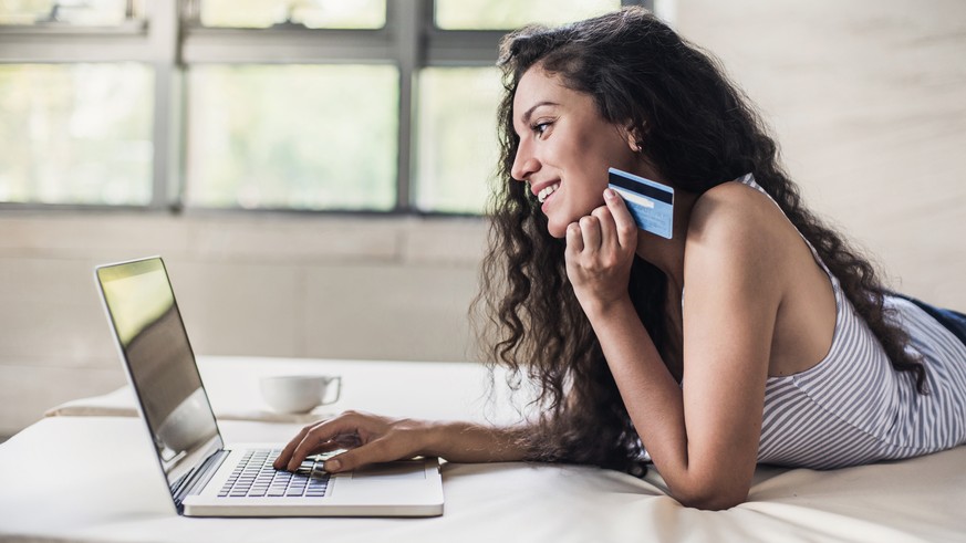 Happy smiling girl using laptop and credit card. Online shopping concept