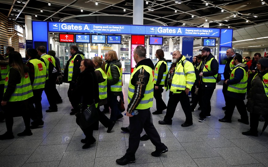 Members of Germany&#039;s union Verdi wear yellow vests as they march in front of Gate A of Duesseldorf Airport during a strike by Verdi, which called on security staff at Duesseldorf, Cologne and Stu ...