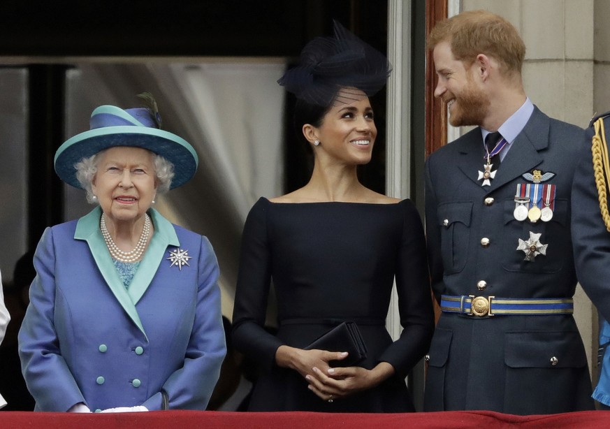 FILE - In this Tuesday, July 10, 2018 file photo Britain&#039;s Queen Elizabeth II, and Meghan the Duchess of Sussex and Prince Harry watch a flypast of Royal Air Force aircraft pass over Buckingham P ...