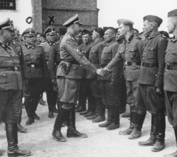 This 1942 photo provided by the the public prosecutor&#039;s office in Hamburg via the United States Holocaust Memorial Museum, shows Heinrich Himmler, center left, shaking hands with new guard recrui ...