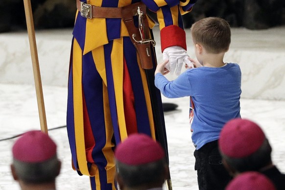A child plays with a Swiss guard after getting up to the area where Pope Francis was speaking, during his weekly general audience in the Paul VI Hall at the Vatican, Wednesday, Nov. 28, 2018. (AP Phot ...