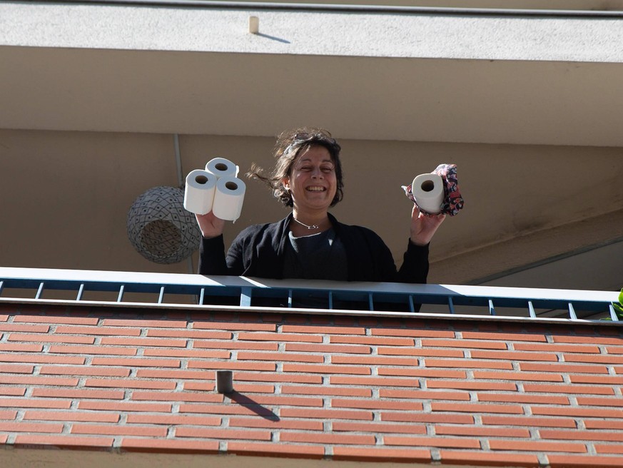 FRANCE - HEALTH - CORONAVIRUS PANDEMIC ILLUSTRATION A woman standing on a balcony smiles while holding several rolls of toilet paper. 19th day of containment in France during the COVID-19 pandemy outb ...