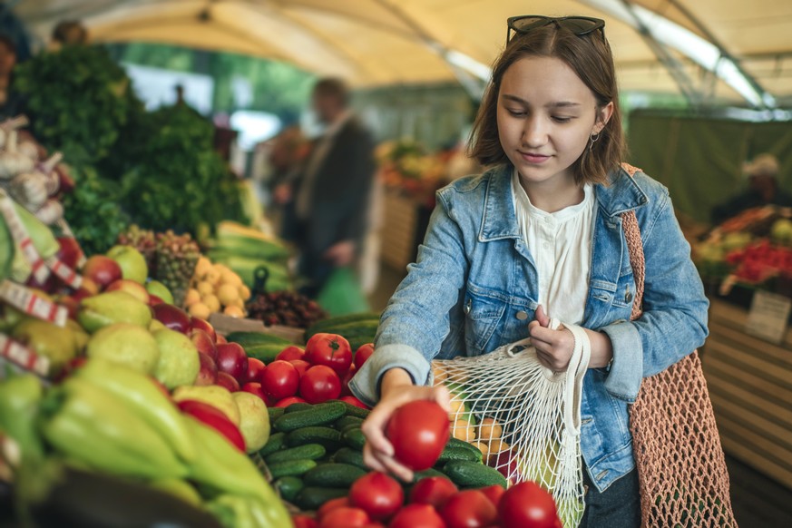 Teenager holding ecologically friendly reusable bag with fruit and vegetables
