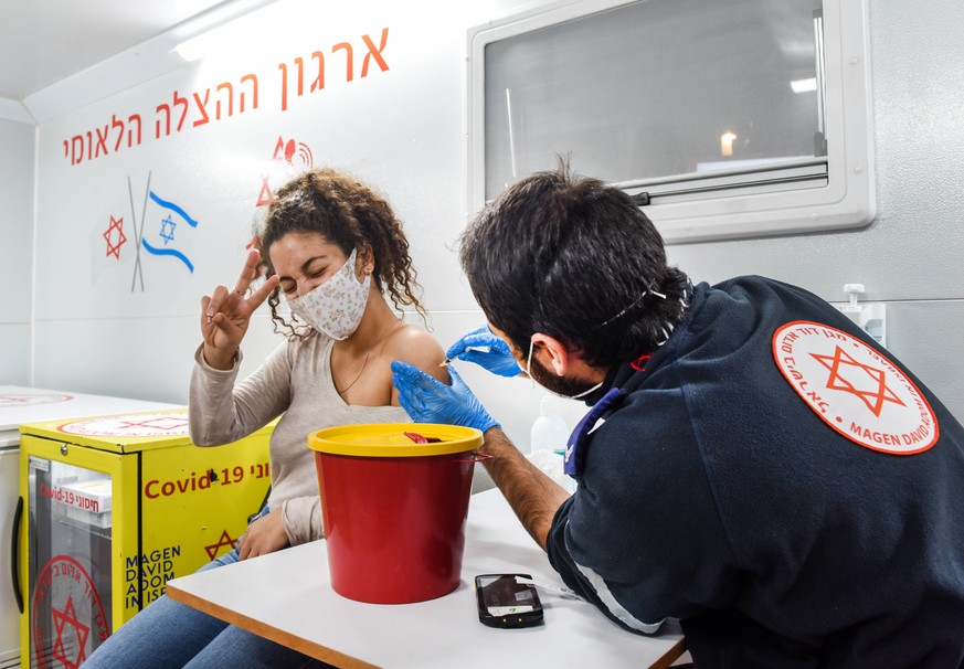 HANDOUT - 18.02.2021, Israel, Tel Aviv: Eine junge Frau wird in Israel in einem mobilen Impf-Bus geimpft. Israels Regierung will so schnell wie m