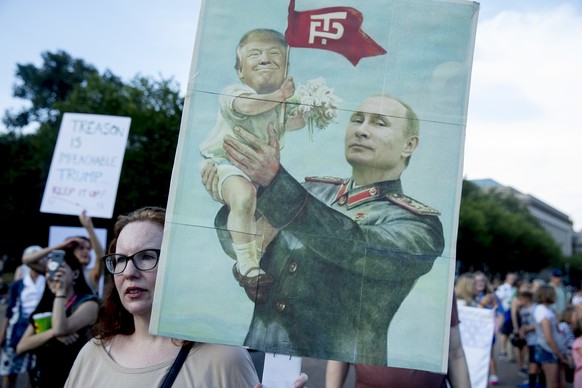 A woman holds a sign depicting Russian President Vladimir Putin and President Donald Trump during a protest outside the White House, Tuesday, July 17, 2018, in Washington. This is the second day in a  ...
