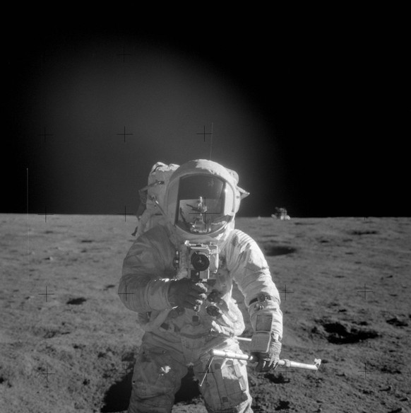 Astronaut Charles Conrad Jr., Apollo 12 commander, using a 70mm handheld Haselblad camera modified for lunar surface usage is photographed trying to snap a photo of his crewmate. He is also holding a  ...
