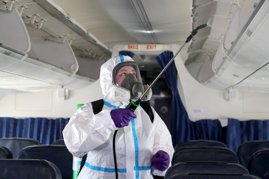 KYIV REGION, UKRAINE - JUNE 13, 2020 - An employee in protective clothing disinfects overhead bins during a demonstration at Boryspil International Airport, Kyiv Region, northern Ukraine. Aircraft dis ...