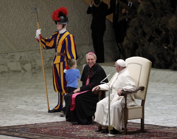 Pope Francis and Archbishop George Gaenswein share a laugh as a child plays with a Swiss guard after getting up to the area where the pontiff was sitting during his weekly general audience, in the Pau ...