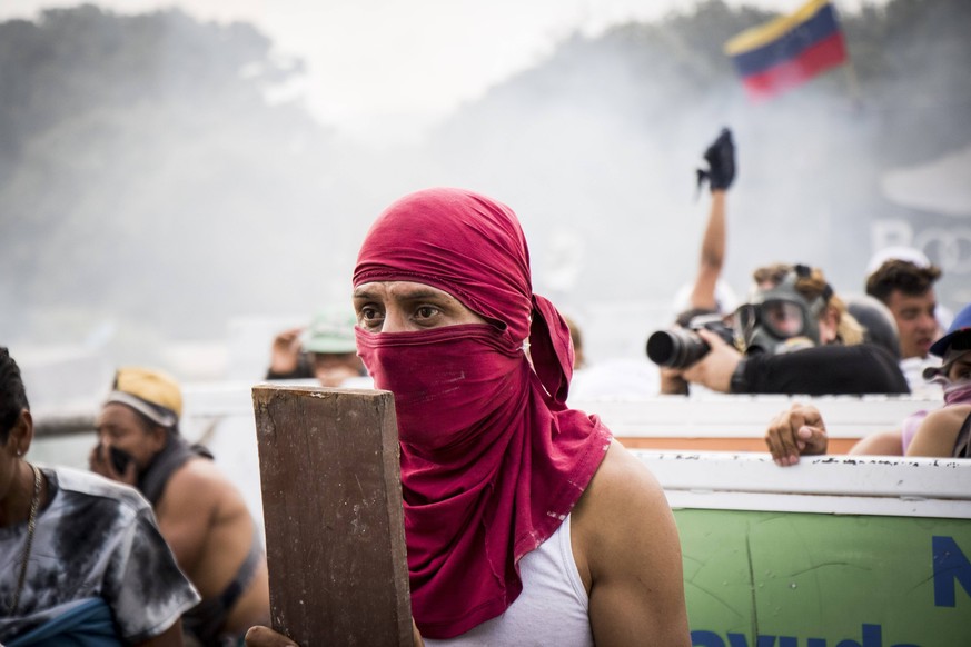 Demonstrators throw stones in clashes with the security forces at the Francisco de Paula Santander international bridge Bridge linking Cucuta, Colombia, and Urena, Venezuela, during an attempt to cros ...