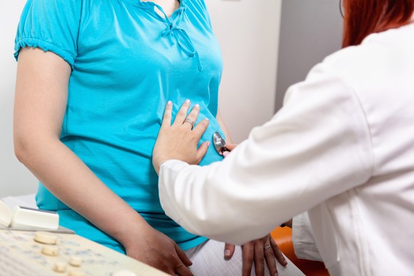Gynecologist Examines A Pregnant Woman By Touching Her Abdomen.