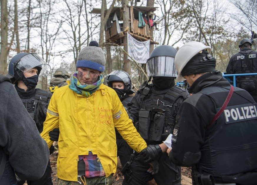 10.11.2020, Hessen, Niederklein: Ein Aktivist (gelbe Jacke), der sich in einem Baumhaus verschanzt hatte, wird von Polizisten festgenommen. Derzeit halten Aktivisten den Dannenröder Forst besetzt und  ...